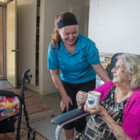 Elderly women drinking tea with a female carer
